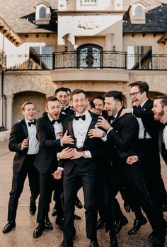 a group of men in tuxedos are posing for a photo outside the mansion