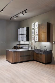 a modern kitchen with wooden cabinets and marble counter tops, along with pictures on the wall