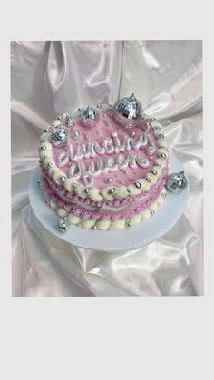 a pink and white cake sitting on top of a table next to a silver cloth