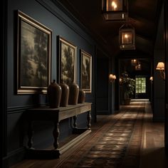 an empty hallway with paintings on the wall and lamps hanging from the ceiling in front of them