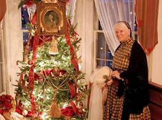 an older woman standing next to a christmas tree