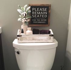 a white toilet sitting in a bathroom next to a sign that says please remain seated for the entire performance