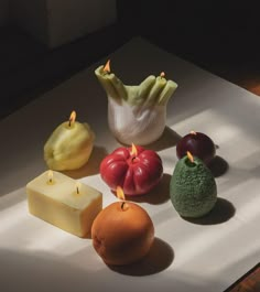 there are many different fruits and cheeses on the table with one candle in the middle