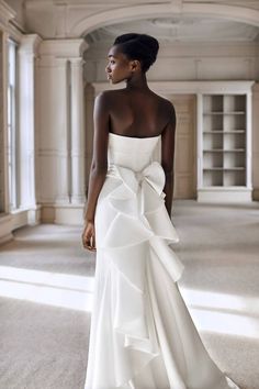 a woman in a white wedding dress with a big bow on her back