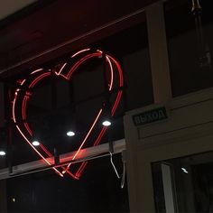 a heart shaped neon sign hanging from the side of a building