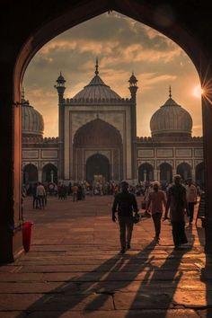 people walking in front of an ornate building at sunset