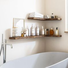 a white bath tub sitting under a window next to a shelf filled with personal care items