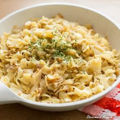 a white bowl filled with pasta on top of a wooden table