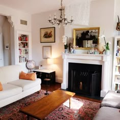 a living room filled with furniture and a fire place under a chandelier above a fireplace