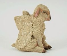 a ceramic figurine of a sheep sitting on the ground