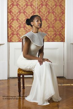 a woman in a white dress sitting on a chair