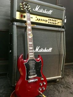 a red guitar sitting next to an amp