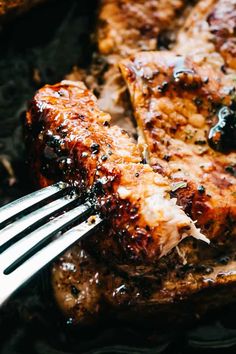 a close up of meat on a plate with a fork sticking out of the meat