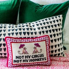 two decorative pillows sitting on top of a bed covered in green and white sheets with black hearts