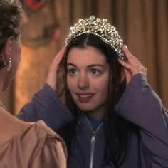 a woman wearing a tiara and looking at another woman