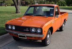 an orange pick up truck parked on the street