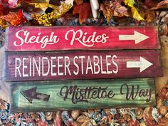 three wooden signs with arrows pointing in different directions and the words sleigh rides, reindeer stables, misterette way