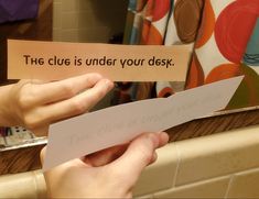 someone holding a piece of paper that says the clue is under your desk