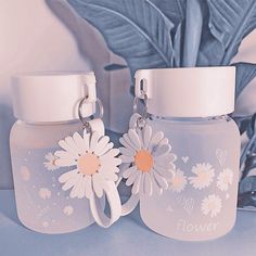 two baby bottles with flowers on them sitting next to each other