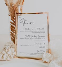 a close up of a menu on a table near a vase with flowers in it