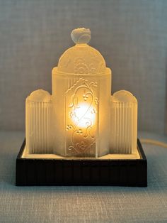 a lit candle sitting on top of a wooden stand with an intricately carved design