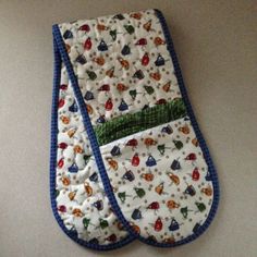 an oven mitt is laying on the floor with blue trimmings and designs