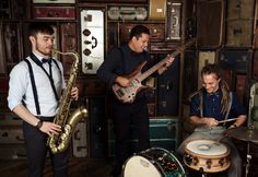 three men are playing instruments in a room