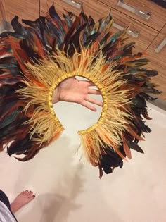 a person standing next to a large piece of art that looks like feathers on the floor