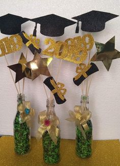 graduation decorations made out of wine bottles with gold ribbon and glitter stars on the top