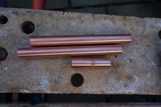 three copper tubes are sitting on a piece of metal