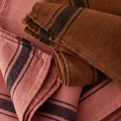 the folded pink and brown plaid blanket is laying on top of another piece of clothing