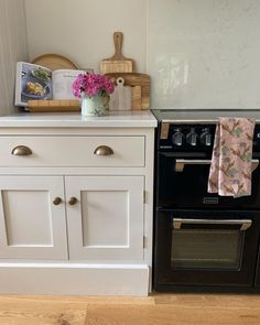 a black stove top oven sitting next to a white cabinet with flowers in vases