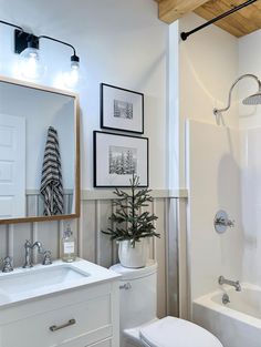 a white bathroom with pictures on the wall above the toilet and bathtub next to it