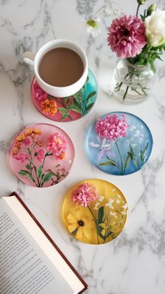 three plates with flowers painted on them next to a cup of coffee and an open book