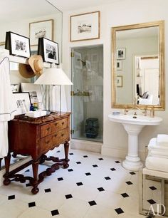 a white bathroom with black and white flooring and pictures on the wall above it