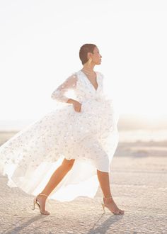 a woman in a white dress is walking on the beach