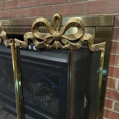 a fireplace with some gold decorations on the top and bottom, sitting in front of a brick wall