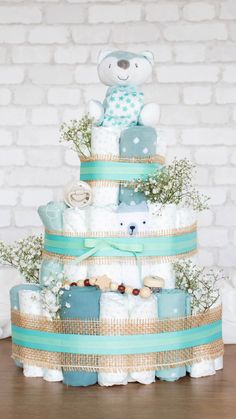 a teddy bear sitting on top of a diaper cake in front of a brick wall