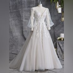 a white wedding dress on display in front of a gray backdrop