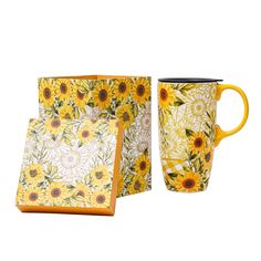 a yellow and white coffee mug with sunflowers on the side, next to a box