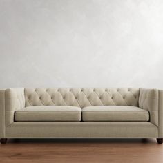 a couch sitting on top of a hard wood floor next to a white painted wall