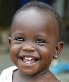 a close up of a child smiling at the camera with an open smile on his face