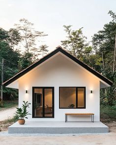 a small white house with two windows and a bench