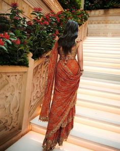 a woman in an orange sari walking up some steps