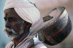 a man with a white turban holding a drum