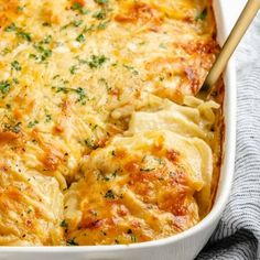 a casserole dish with cheese and parsley in it on a blue towel