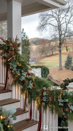 christmas garland on the front porch with lights and greenery hanging from it's railing