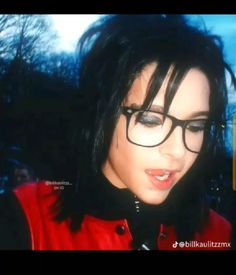 a woman with black hair wearing glasses and a red jacket