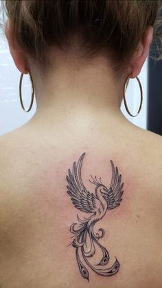 a woman's back with a bird tattoo on her upper and lower back shoulder