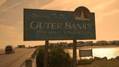 there is a sign that says welcome to the outer banks paradise on earth in front of some water